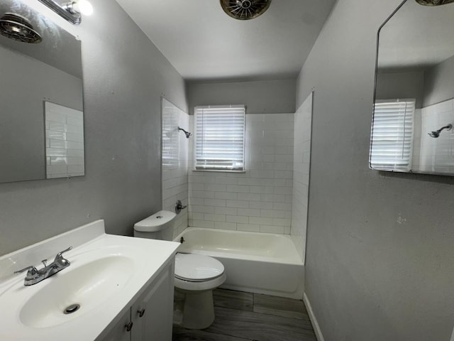 full bathroom featuring vanity, tiled shower / bath, and toilet