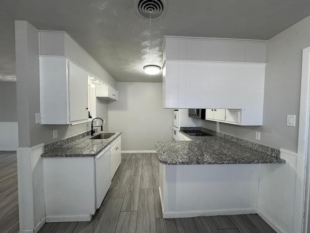 kitchen featuring dishwasher, white cabinetry, sink, kitchen peninsula, and black electric cooktop