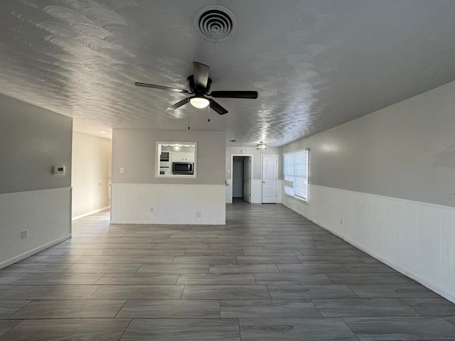 unfurnished living room featuring a textured ceiling and ceiling fan