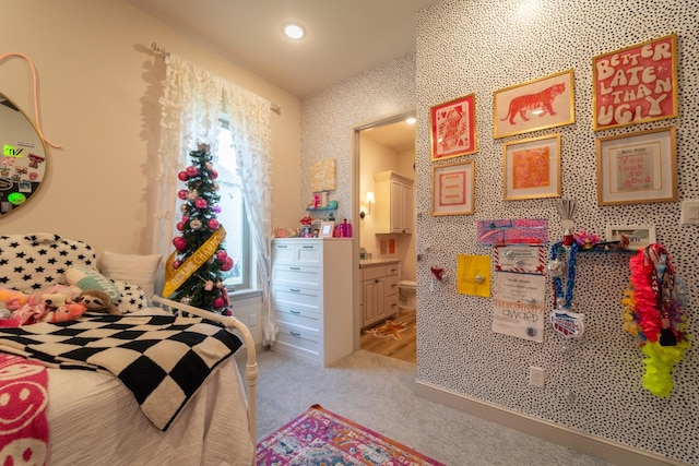 bedroom with ensuite bathroom and light carpet