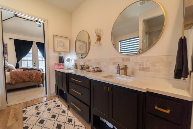 bathroom featuring french doors, vanity, wood-type flooring, and decorative backsplash