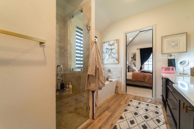 bathroom featuring hardwood / wood-style flooring, shower with separate bathtub, vaulted ceiling, and vanity