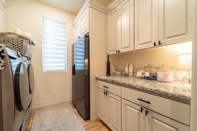 laundry room featuring cabinets, light hardwood / wood-style flooring, and washing machine and clothes dryer