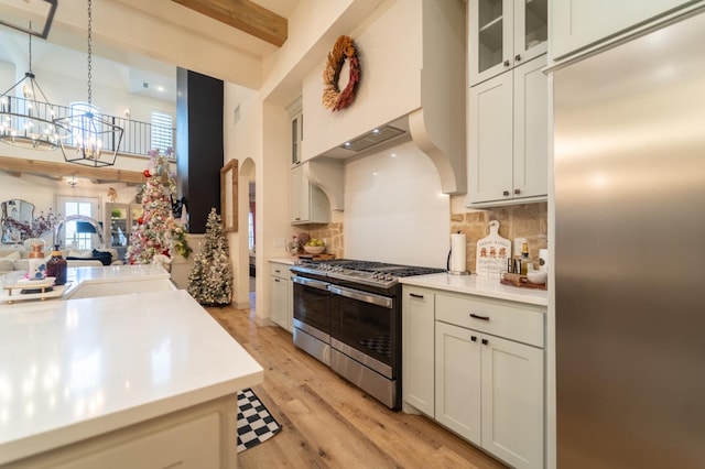 kitchen featuring decorative light fixtures, sink, white cabinets, stainless steel appliances, and light hardwood / wood-style flooring