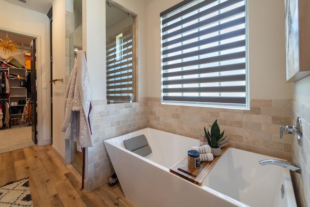 bathroom featuring tile walls, hardwood / wood-style flooring, and a bathing tub