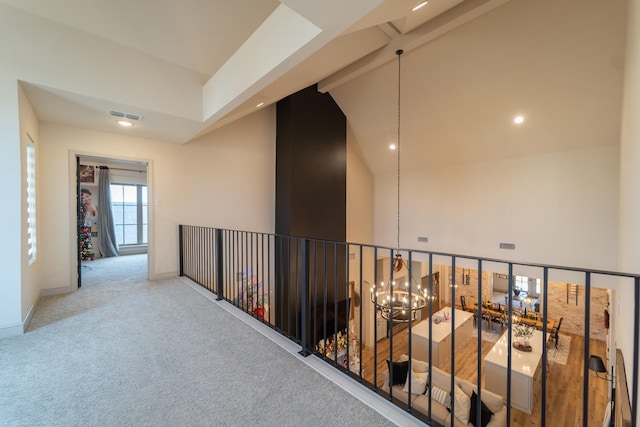 corridor with an inviting chandelier, beam ceiling, carpet floors, and high vaulted ceiling