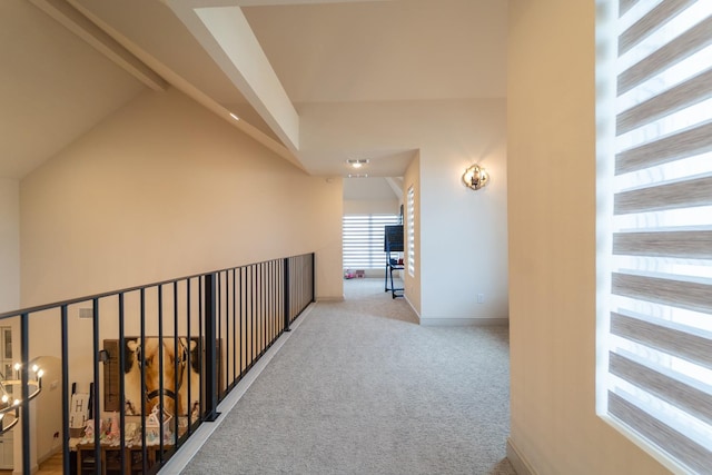 hallway featuring lofted ceiling with beams and light carpet