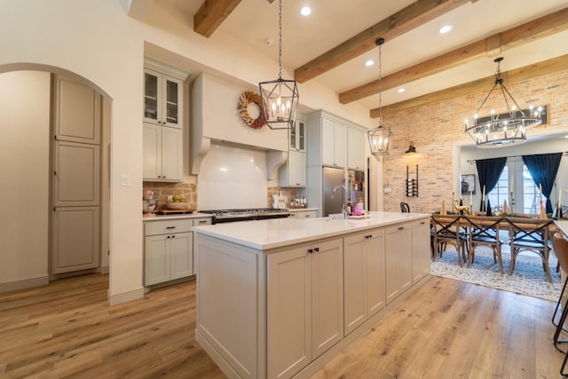 kitchen featuring hanging light fixtures, a center island with sink, a notable chandelier, and light wood-type flooring