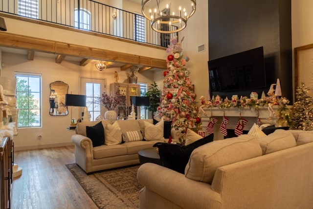 living room with ornate columns, a towering ceiling, hardwood / wood-style floors, and a notable chandelier