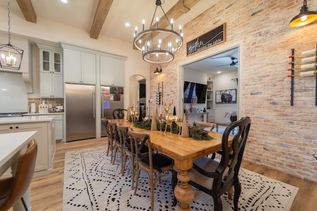 dining area with beamed ceiling, brick wall, ceiling fan with notable chandelier, and light wood-type flooring