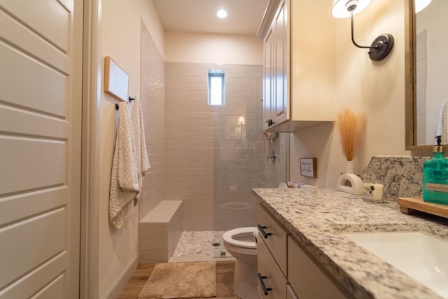 bathroom featuring vanity, tiled shower, and toilet