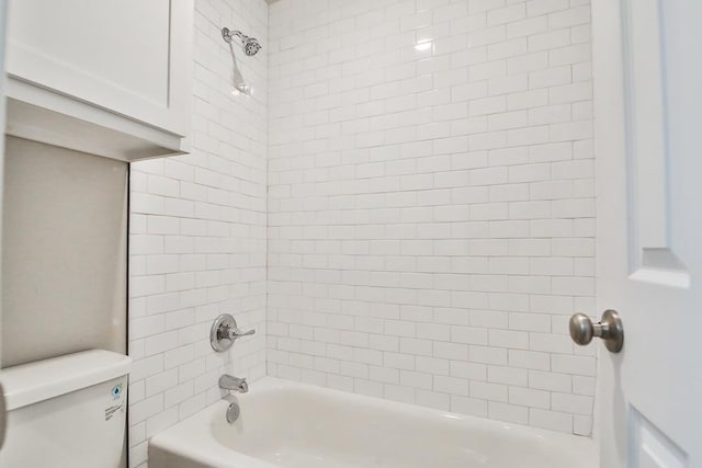 bathroom featuring toilet and tiled shower / bath