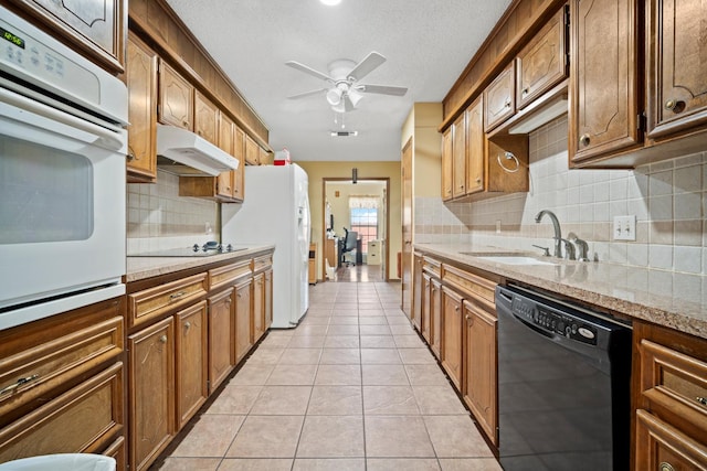 kitchen with light tile patterned flooring, sink, light stone counters, ceiling fan, and black appliances