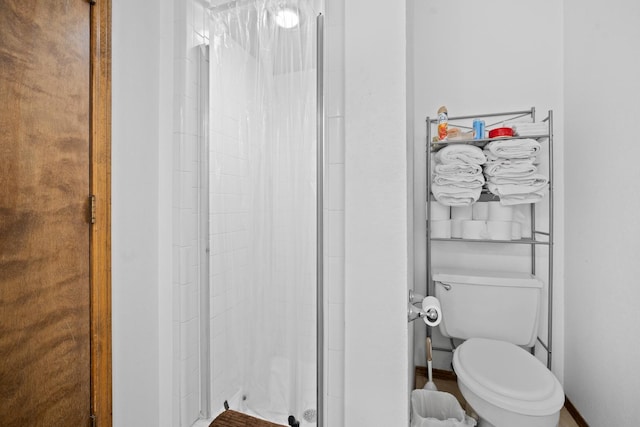 bathroom with a shower with shower door and toilet