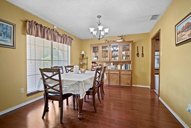 dining room featuring dark wood-type flooring, a chandelier, and a textured ceiling