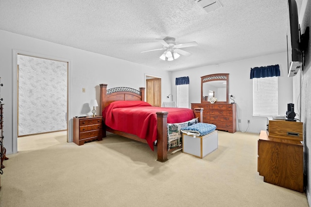 carpeted bedroom with ceiling fan and a textured ceiling