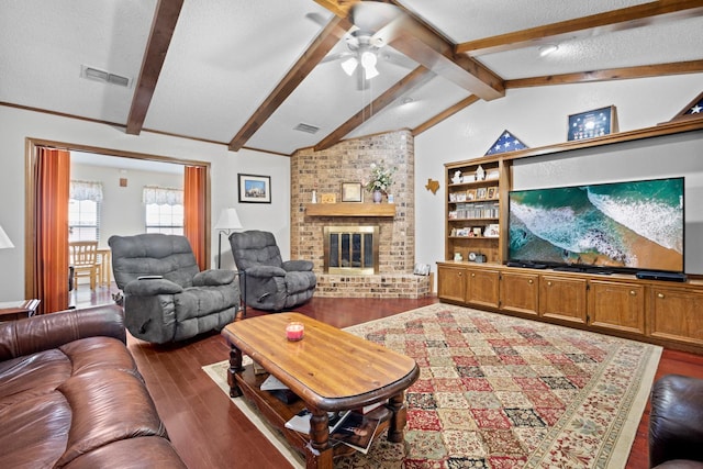 living room with hardwood / wood-style flooring, ceiling fan, a fireplace, lofted ceiling with beams, and a textured ceiling