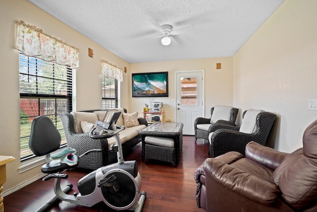 living room featuring ceiling fan, plenty of natural light, dark hardwood / wood-style floors, and a textured ceiling