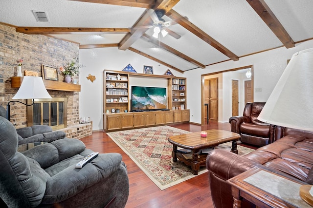 living room featuring lofted ceiling with beams, a textured ceiling, dark hardwood / wood-style floors, ceiling fan, and a fireplace