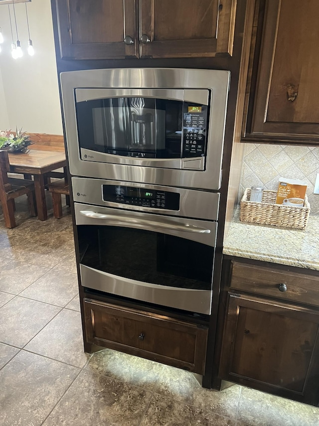 room details with dark brown cabinetry, stainless steel appliances, light stone counters, and decorative backsplash