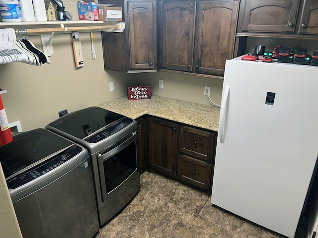 laundry area with washing machine and clothes dryer and cabinet space
