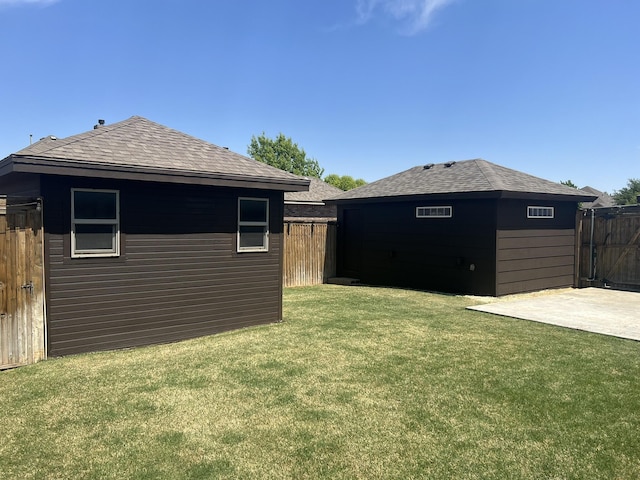 view of yard with a patio, fence, and an outbuilding