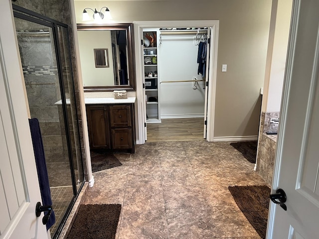 bathroom featuring a spacious closet, a shower stall, and vanity