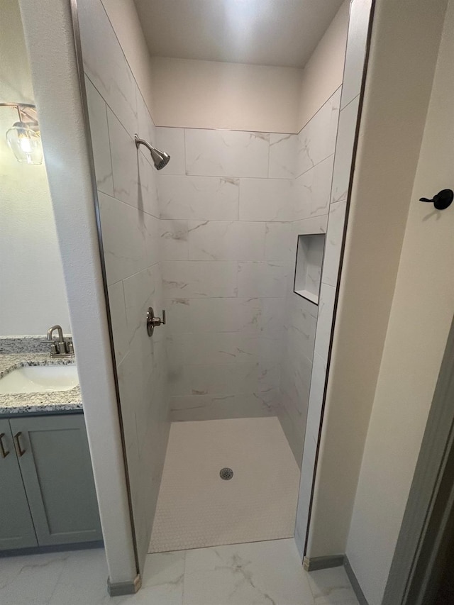 bathroom with a tile shower and vanity