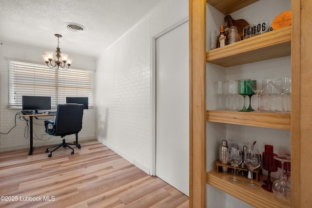 6405 Joliet Ave, Lubbock, TX 79413 - home office with wood finished floors, a chandelier, brick wall, crown molding, and a textured ceiling