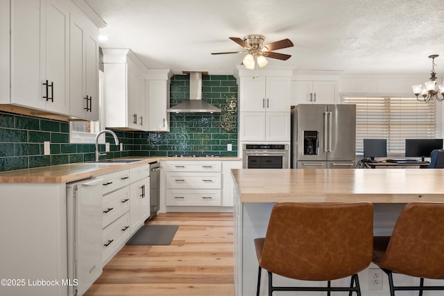 6405 Joliet Ave, Lubbock, TX 79413 - kitchen featuring stainless steel appliances, wall chimney exhaust hood, a ceiling fan, a breakfast bar area, and white cabinets