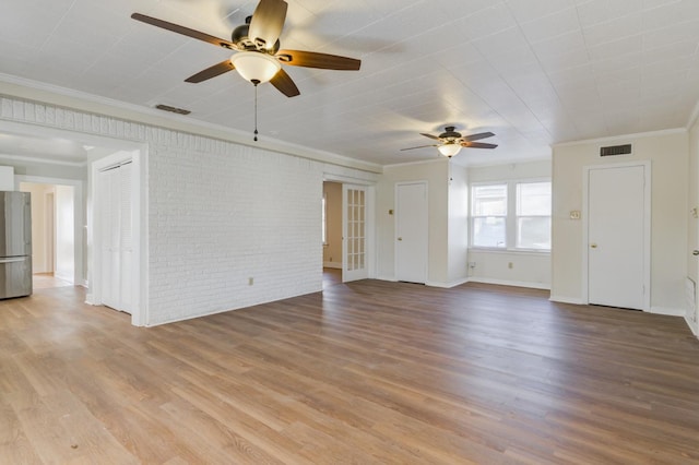 unfurnished living room with ceiling fan, ornamental molding, brick wall, and light hardwood / wood-style floors