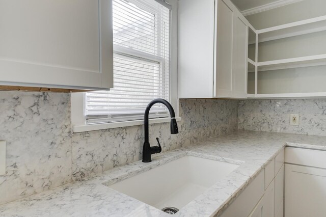 details featuring sink, white cabinets, light stone counters, and decorative backsplash