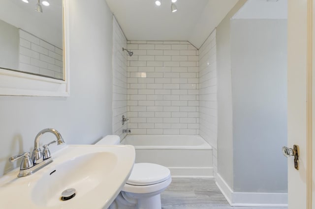 full bathroom featuring hardwood / wood-style flooring, tiled shower / bath, sink, and toilet