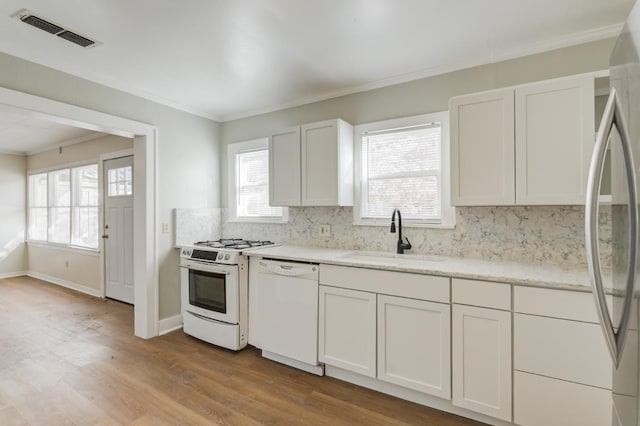 kitchen featuring sink, white appliances, white cabinets, and backsplash