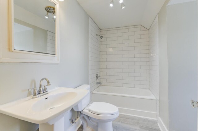 full bathroom featuring hardwood / wood-style flooring, tiled shower / bath, toilet, and sink