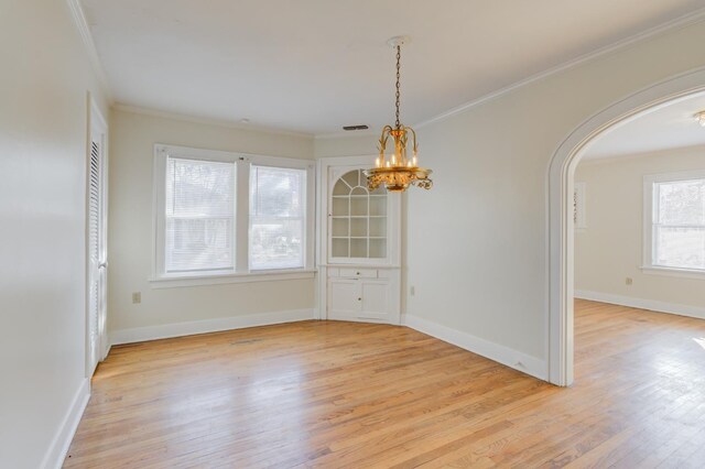 unfurnished dining area featuring an inviting chandelier, ornamental molding, and light wood-type flooring