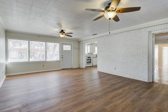 unfurnished living room featuring hardwood / wood-style flooring, ornamental molding, and brick wall