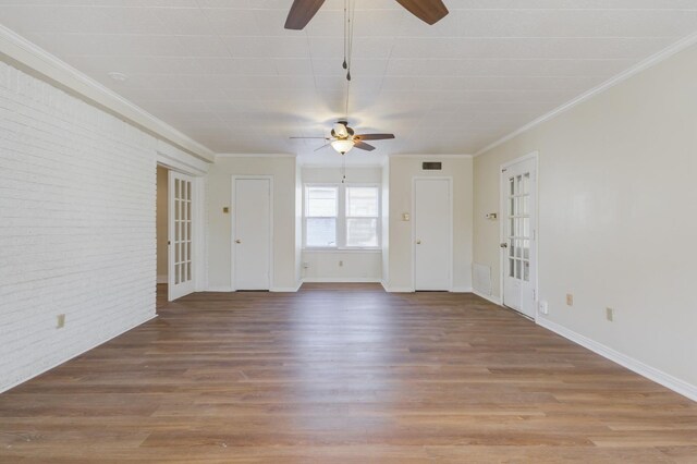 unfurnished living room with wood-type flooring, brick wall, ornamental molding, and ceiling fan