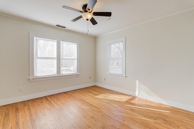 empty room featuring ceiling fan, a wealth of natural light, ornamental molding, and wood-type flooring