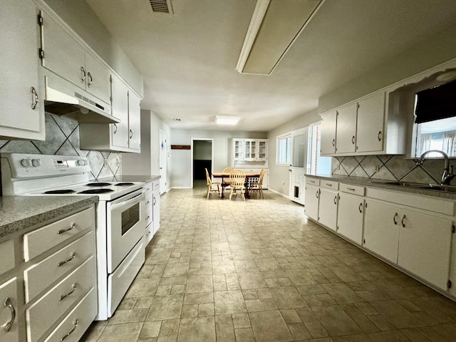kitchen with tasteful backsplash, visible vents, a sink, under cabinet range hood, and electric range