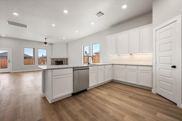 kitchen featuring white cabinetry, stainless steel dishwasher, light stone counters, and light hardwood / wood-style flooring