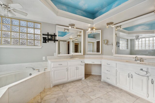 bathroom featuring a raised ceiling, vanity, a washtub, and ceiling fan