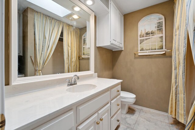 bathroom featuring tile patterned floors, vanity, toilet, and a skylight