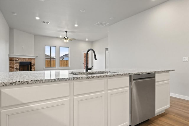 kitchen with sink, ceiling fan, white cabinetry, a fireplace, and light stone countertops