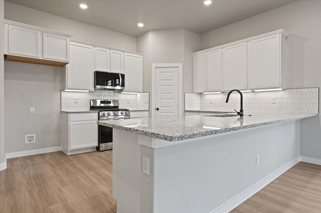 kitchen featuring appliances with stainless steel finishes, sink, white cabinets, and kitchen peninsula