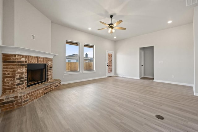 unfurnished living room with a brick fireplace, hardwood / wood-style flooring, and ceiling fan