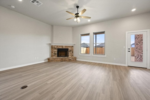 unfurnished living room featuring a brick fireplace, ceiling fan, and light hardwood / wood-style flooring