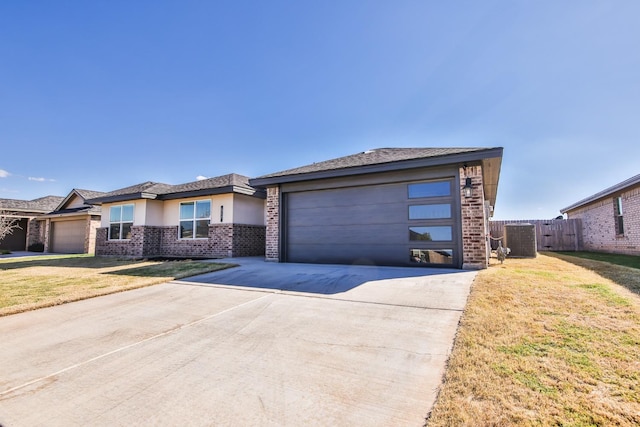 view of front of home with a garage, a front yard, and central AC unit