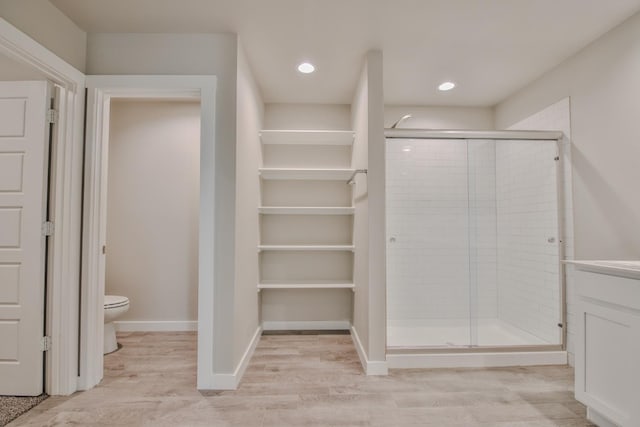 bathroom featuring hardwood / wood-style floors, toilet, and walk in shower