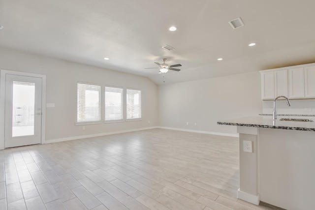 unfurnished living room featuring lofted ceiling, sink, ceiling fan, and light wood-type flooring